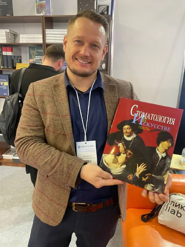 Валерий Скрынников с книгой «Стоматология в искусстве» на стоматологической выставке